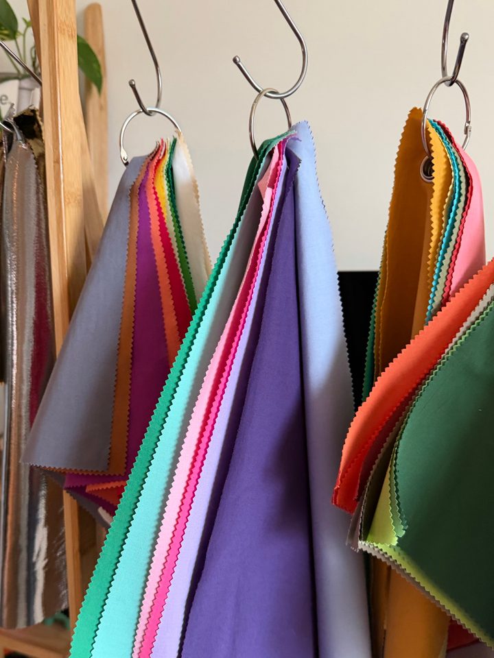 Sets of colour drapes on silver hooks, fanned out in lilac, mint, pink, coral and deep green