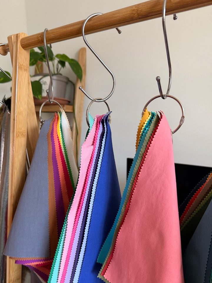 Drape sets hanging from a bamboo rail, with grey-blue, royal blue and coral pink at the front