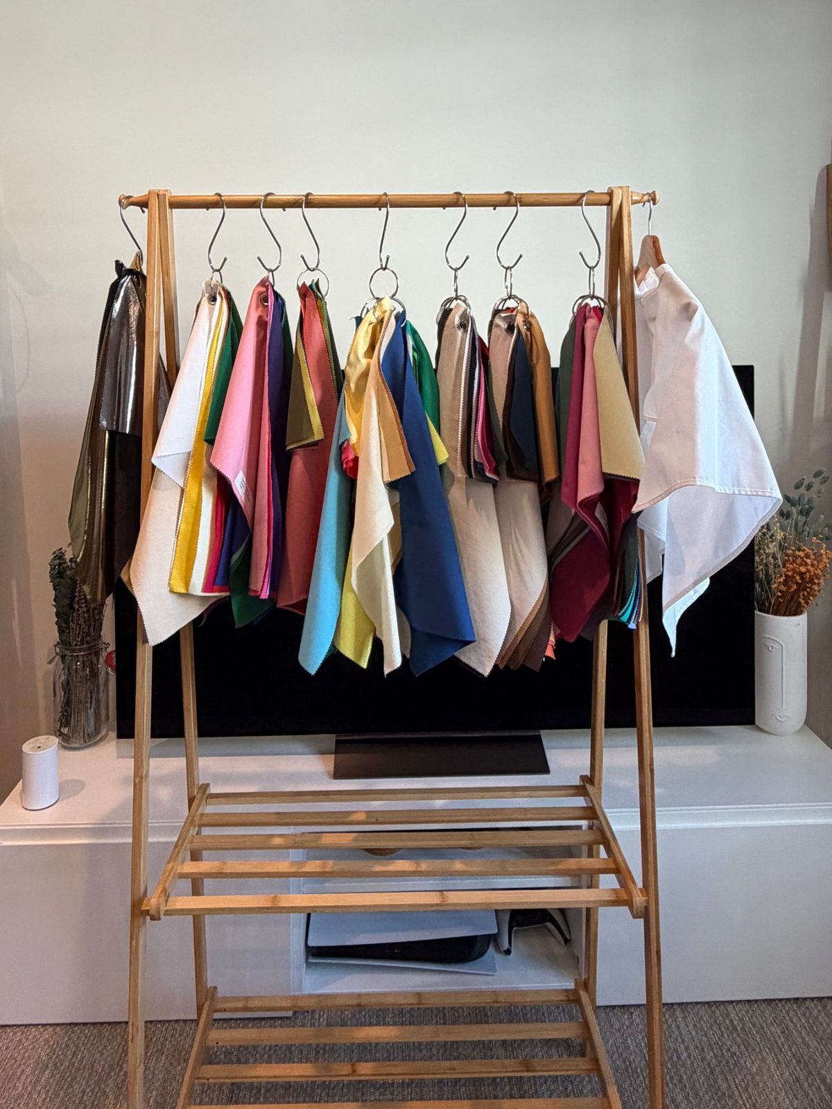Shann&rsquo;s colour drapes hanging in sets from a wooden rail, from soft neutrals to clear blues, pinks and greens